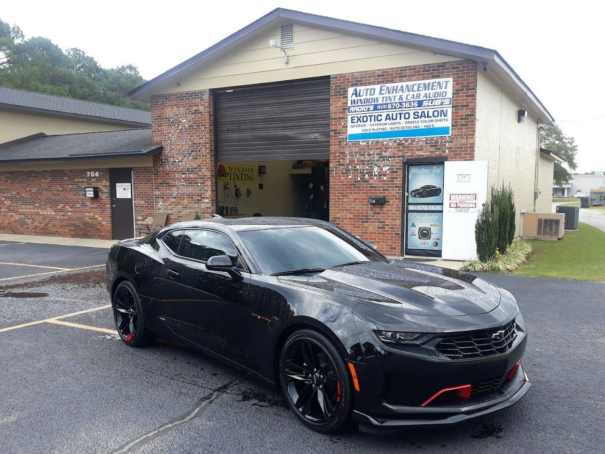 A black car is parked in front of a brick building.