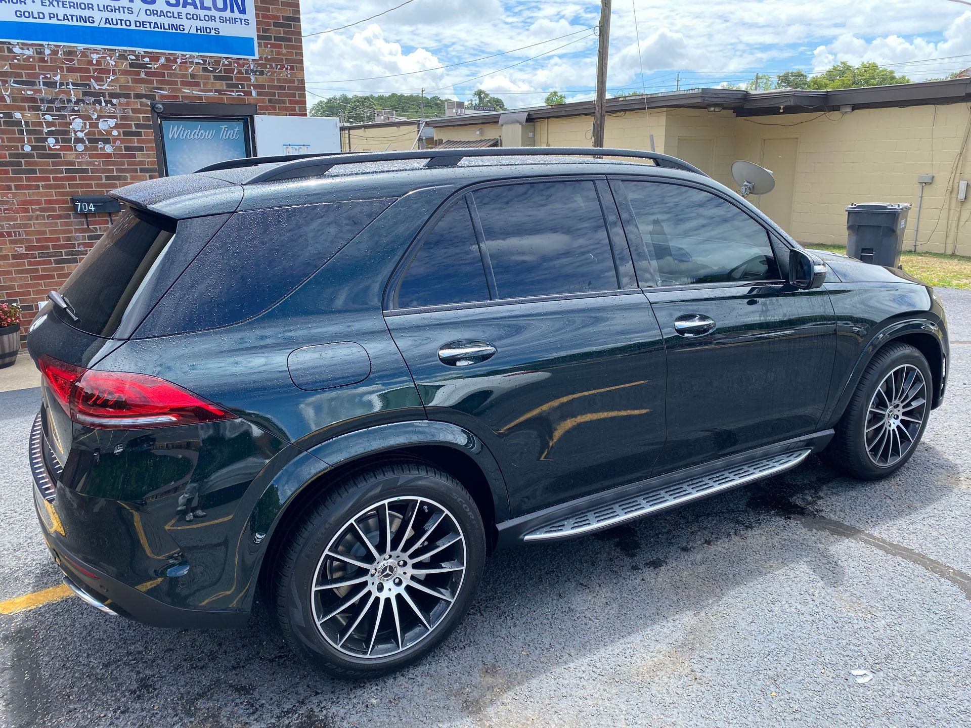 A black suv is parked in a parking lot in front of a brick building.