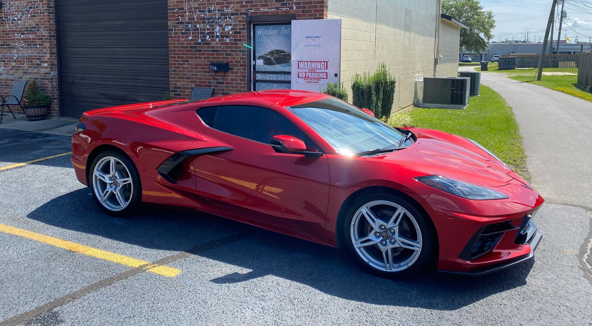 A red sports car is parked in a parking lot in front of a building.