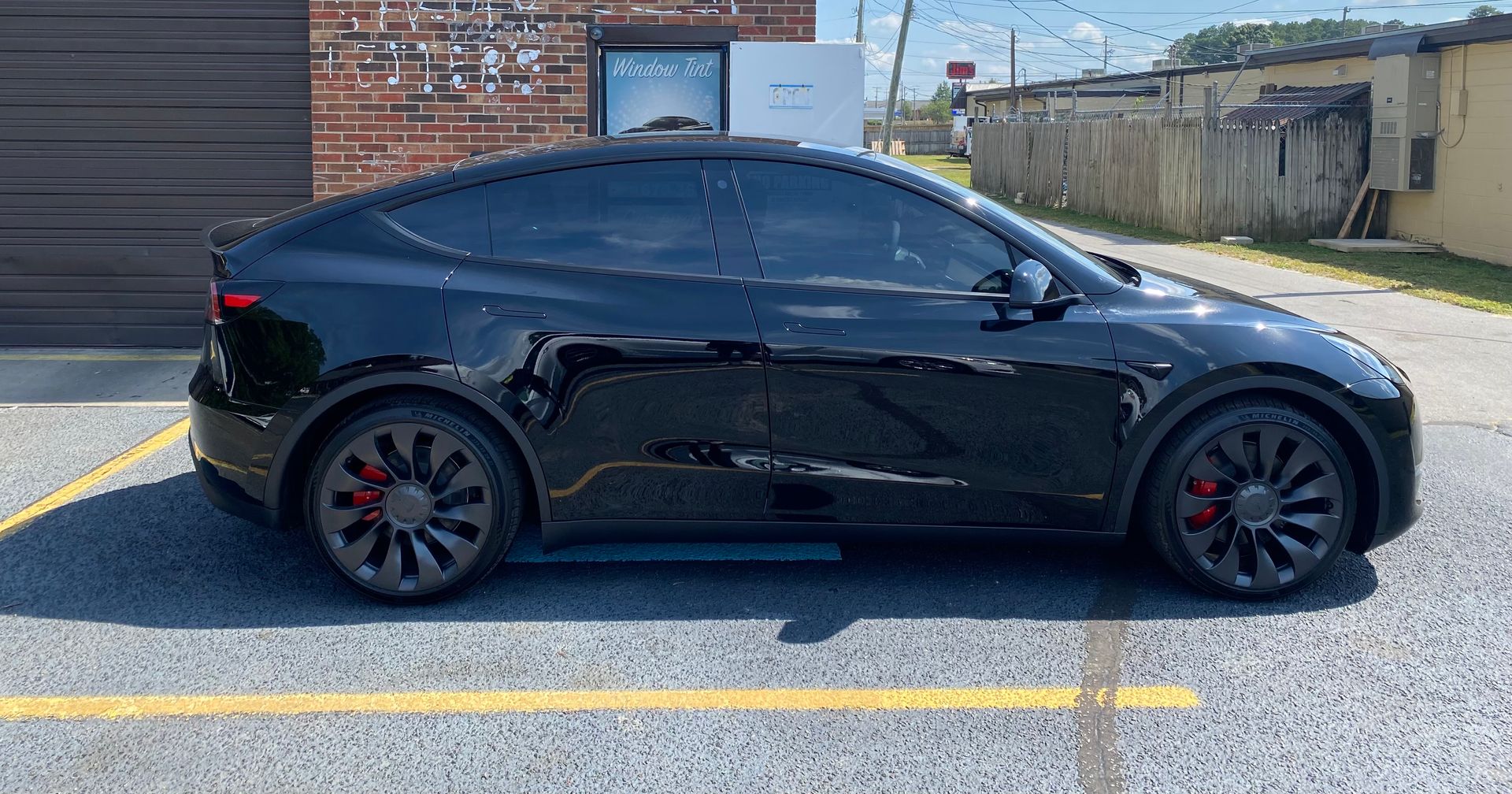 A black tesla model y is parked in a parking lot.