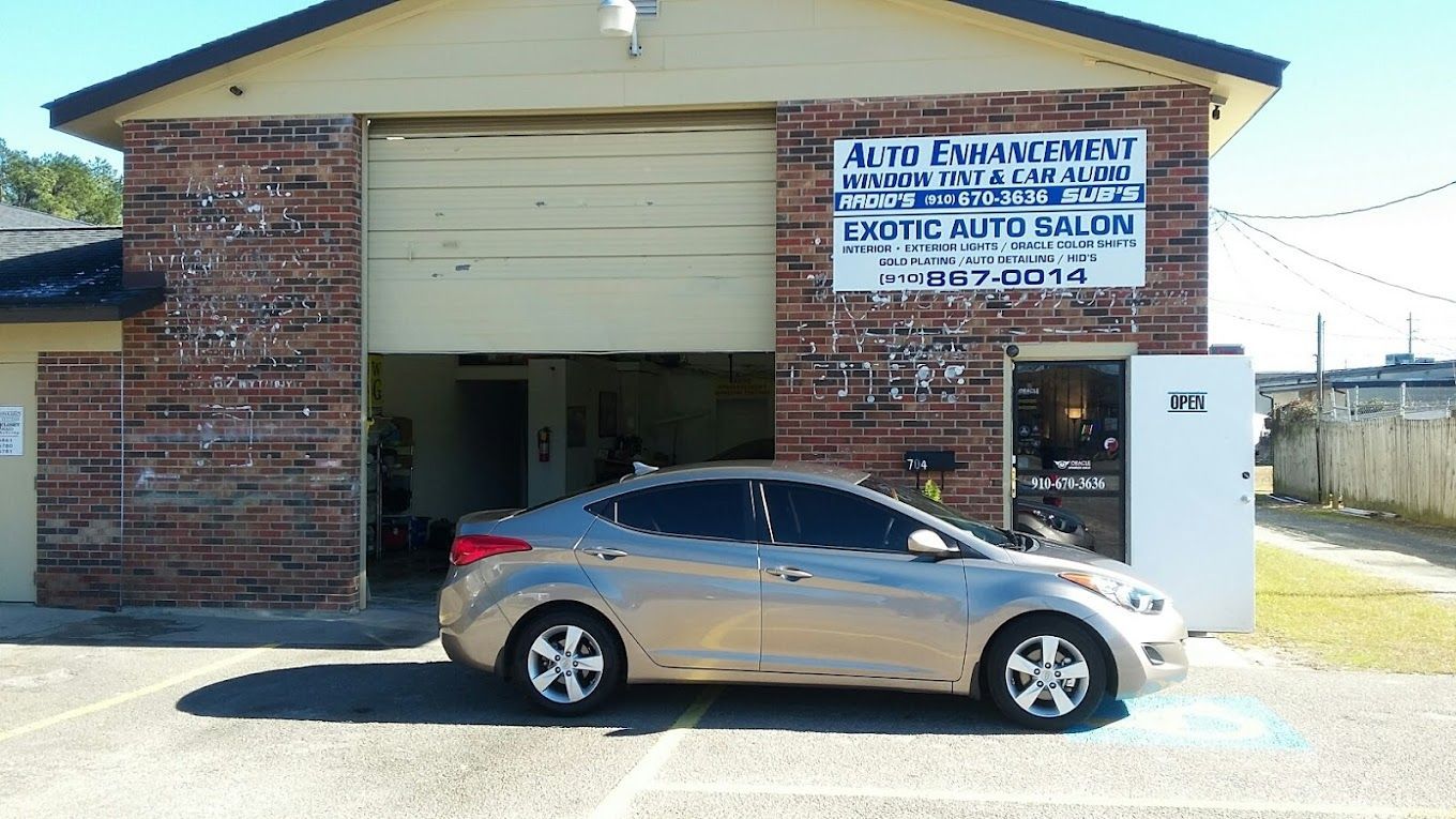 A silver car is parked in front of a brick building.