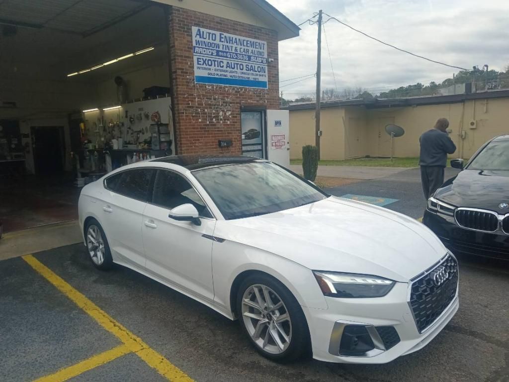 A white audi a5 is parked in a parking lot in front of a car wash.