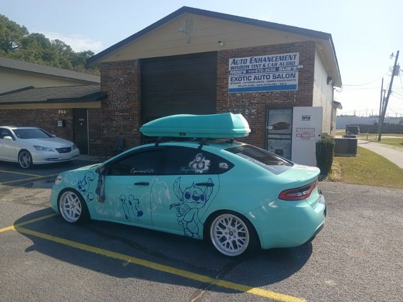A car with a roof box on top of it is parked in front of a building.
