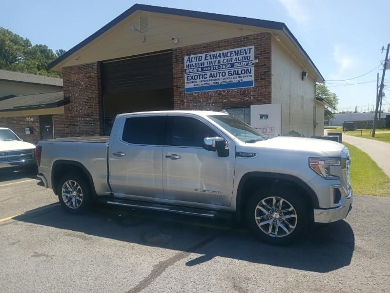 A silver pickup truck is parked in front of a brick building.