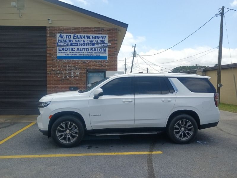 A white suv is parked in a parking lot in front of a brick building.
