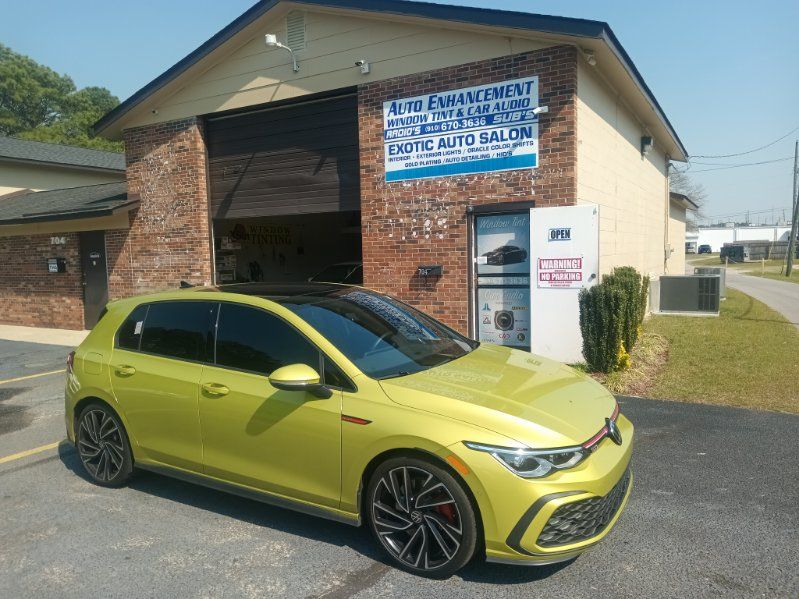 A yellow car is parked in front of a brick building.