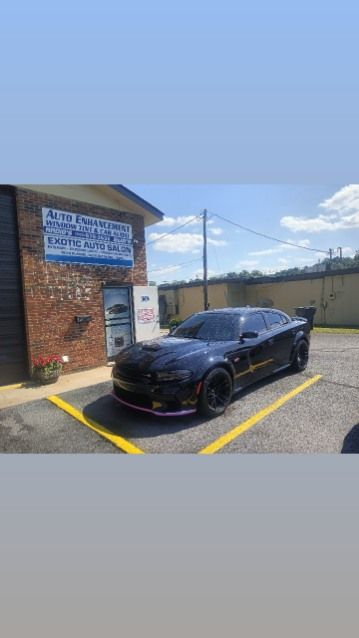 A black car is parked in a parking lot in front of a building.