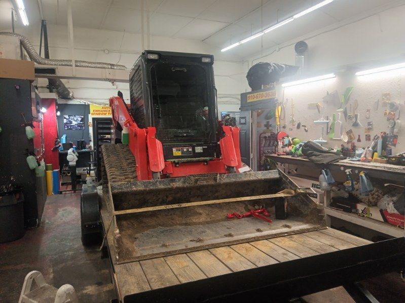 A bulldozer is sitting on top of a wooden trailer in a garage.