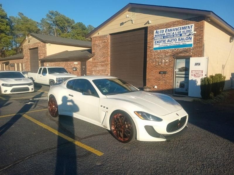 A white car is parked in front of a building.