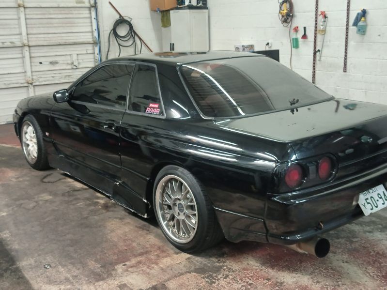 A black nissan skyline is parked in a garage