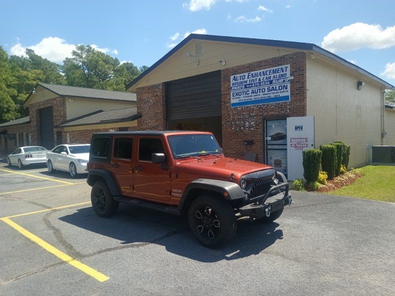 A red jeep is parked in front of a building.