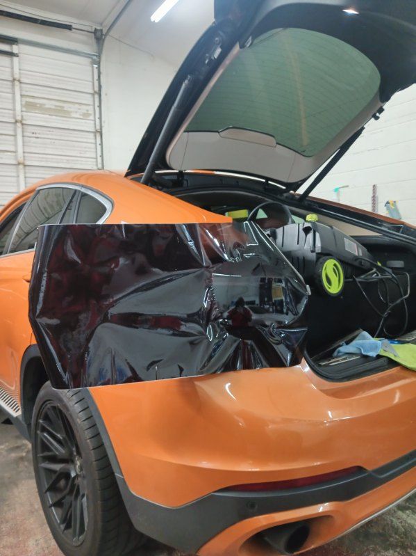 An orange car with the trunk open is sitting in a garage.