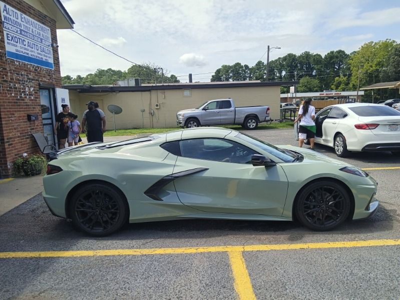 A green sports car is parked in a parking lot.