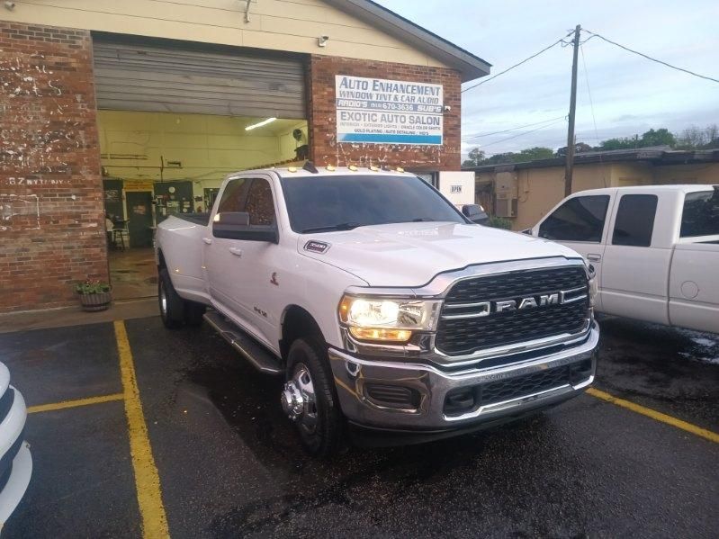 A white ram truck is parked in a parking lot in front of a garage.