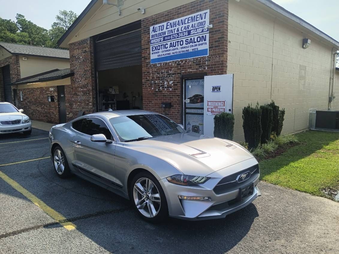 A silver ford mustang is parked in front of a building.