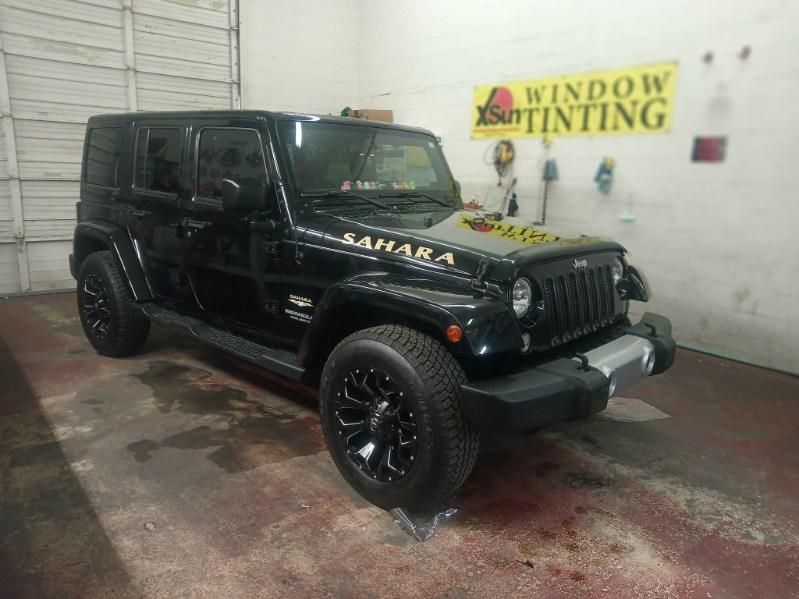A black jeep is parked in front of a window tinting sign.