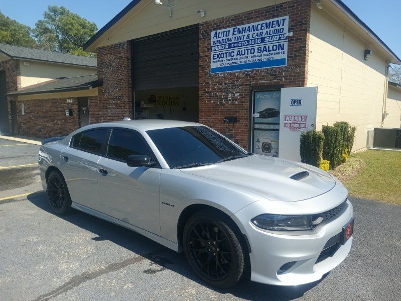 A white dodge charger is parked in front of a brick building.