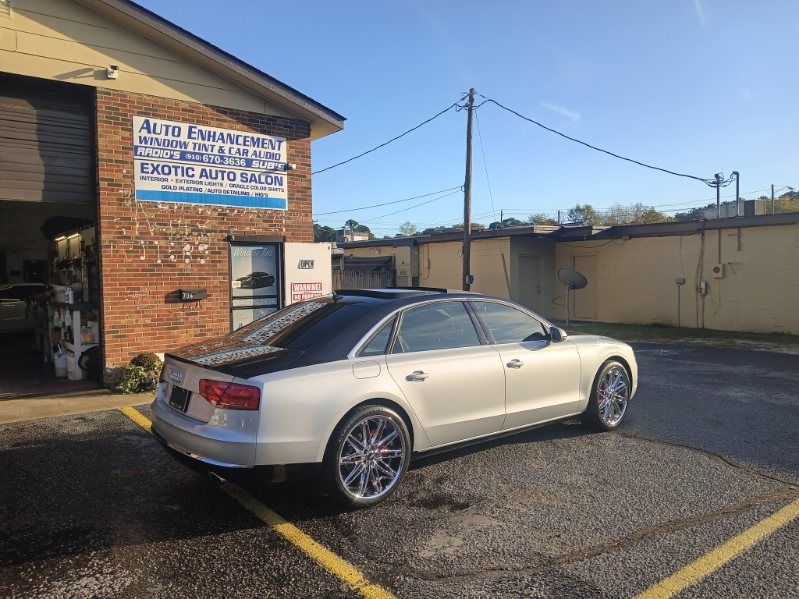 A silver car is parked in a parking lot in front of a building.