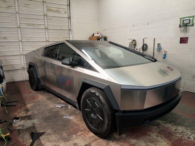 A silver tesla cybertruck is parked in a garage.