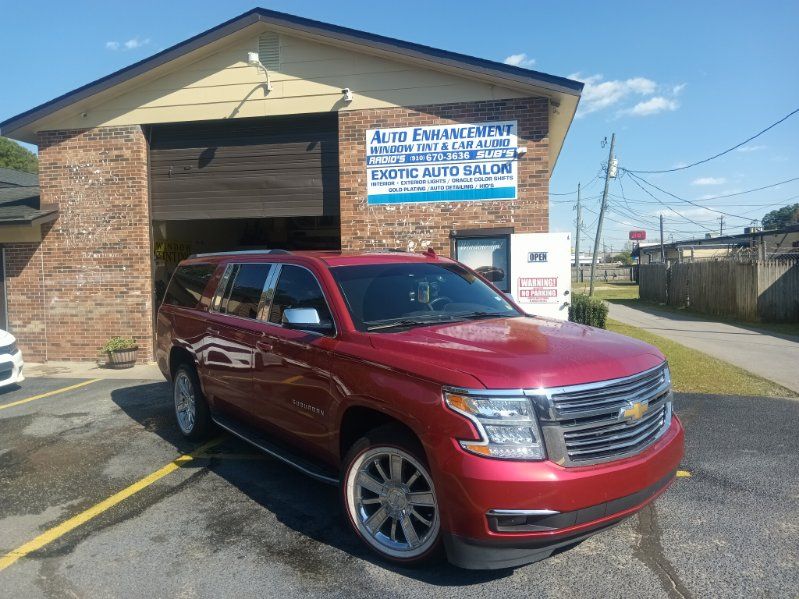 A red suv is parked in front of a brick building.