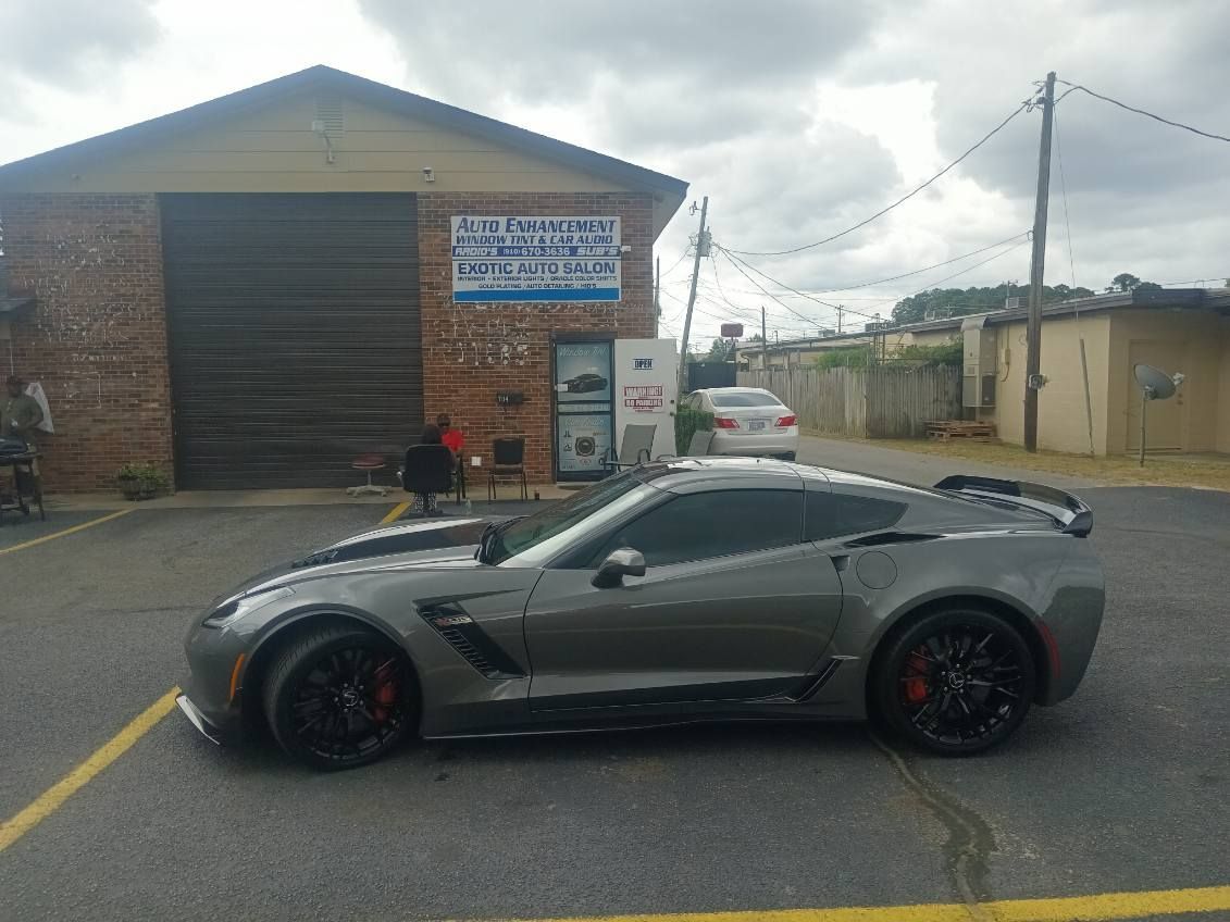 A gray sports car is parked in a parking lot in front of a building.