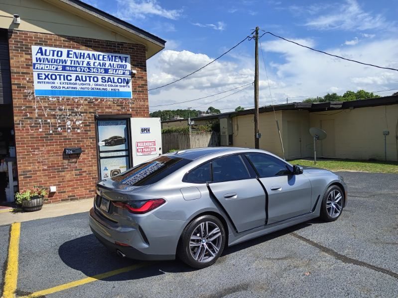 A silver car is parked in front of a brick building.