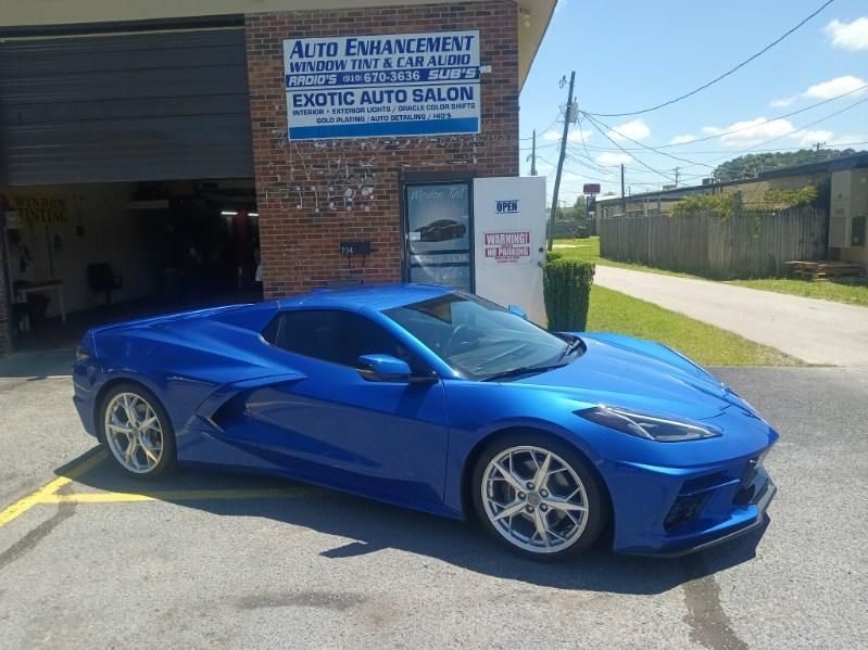 A blue sports car is parked in front of a brick building.