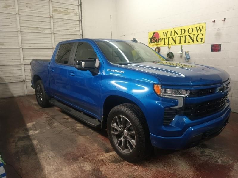 A blue truck is parked in a garage next to a sign that says window tinting.