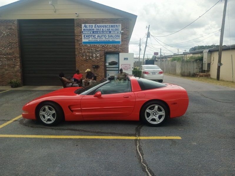 A red sports car is parked in a parking lot in front of a building.