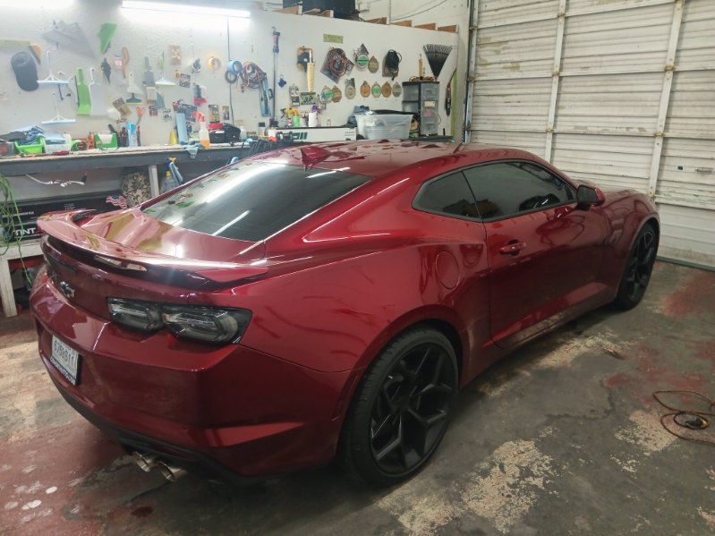A red chevrolet camaro is parked in a garage.