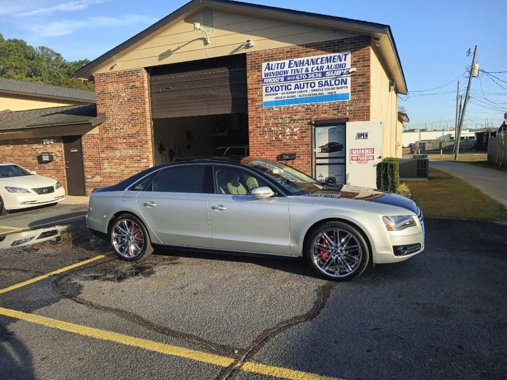 A silver car is parked in front of a brick building.