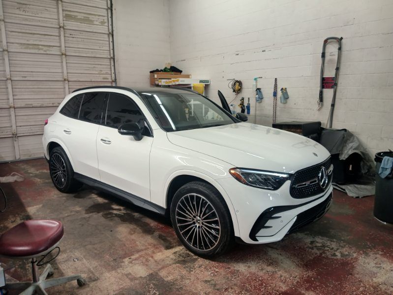 A white suv is parked in a garage next to a chair.