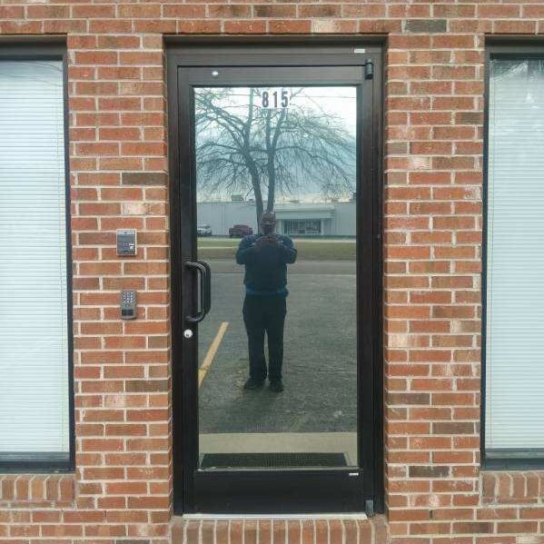 A man is taking a picture of himself in front of a door that says 215