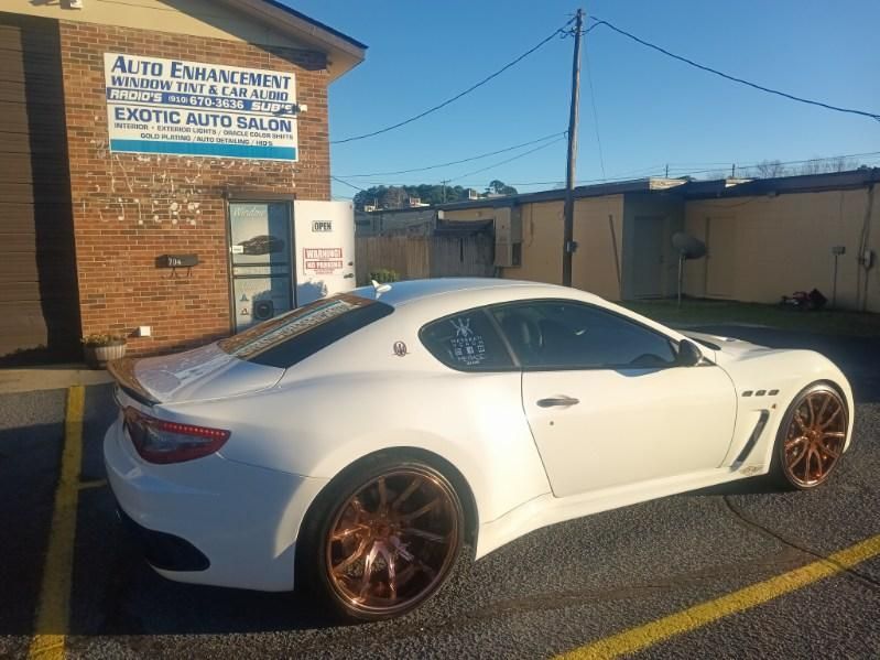 A white sports car is parked in a parking lot in front of a building.