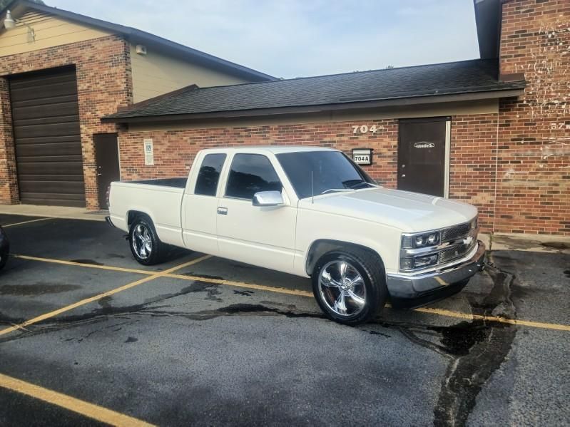A white truck is parked in a parking lot in front of a brick building.