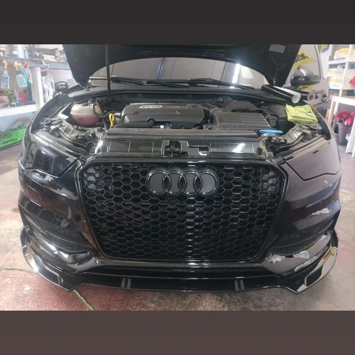 A black audi with the hood open in a garage