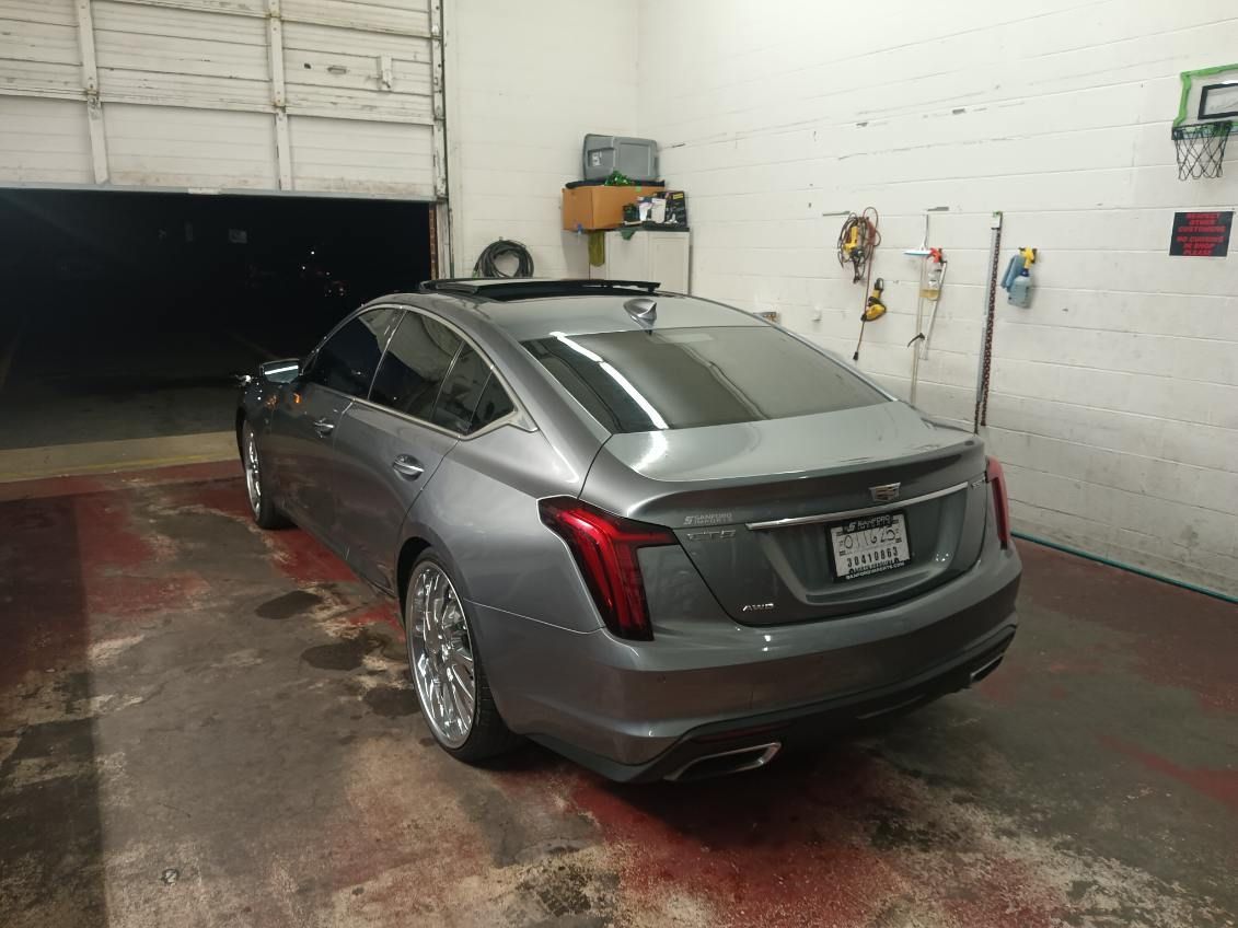 A gray car is parked in a garage next to a garage door.