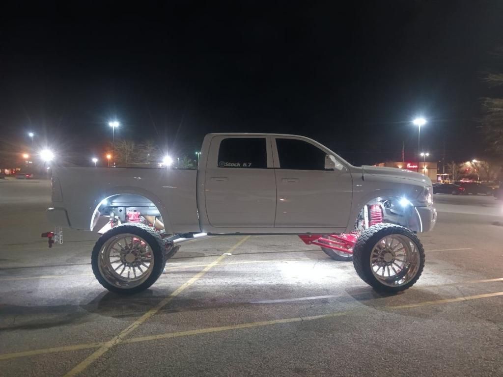 A white truck is parked in a parking lot at night.