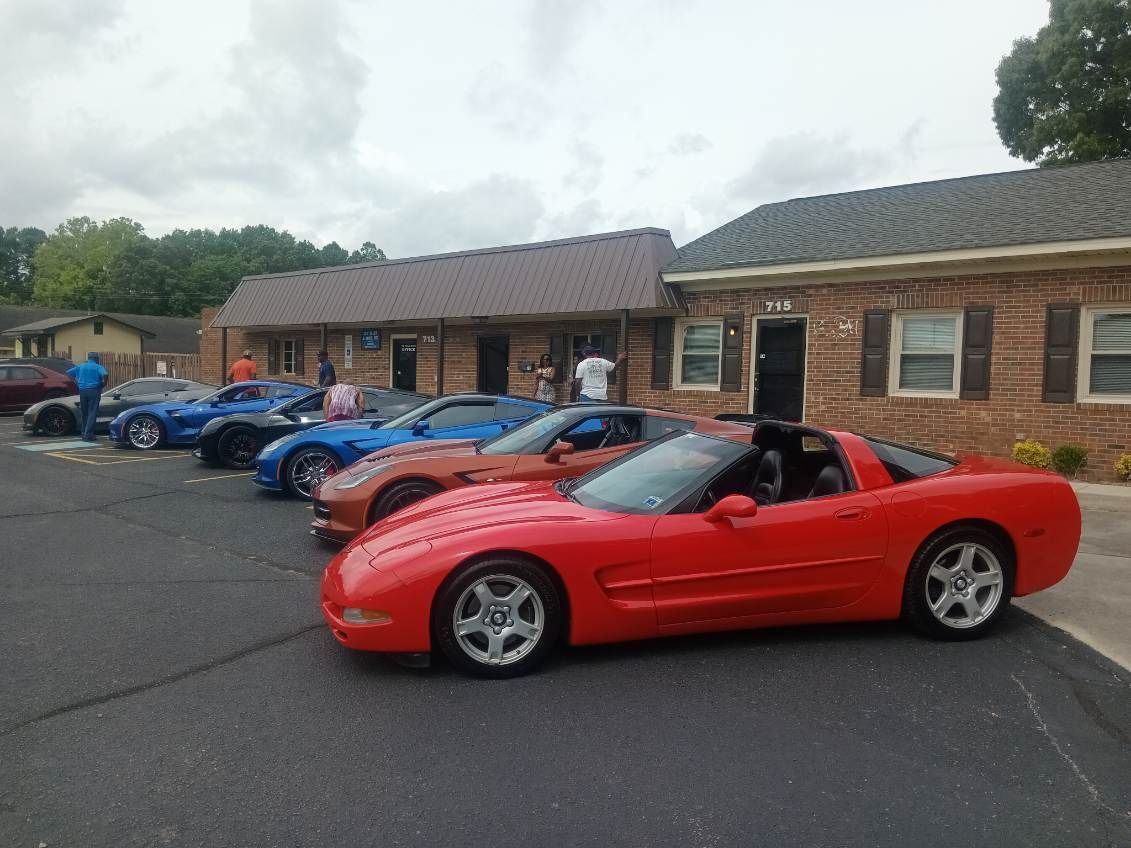 A row of red sports cars are parked in front of a brick building.