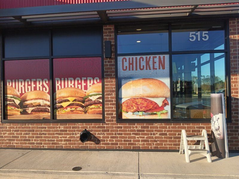 A brick building with a window that says chicken burgers