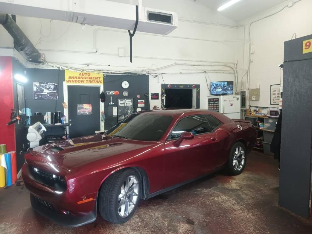A red dodge challenger is parked in a garage.
