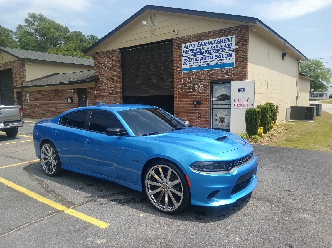 A blue dodge charger is parked in front of a building.