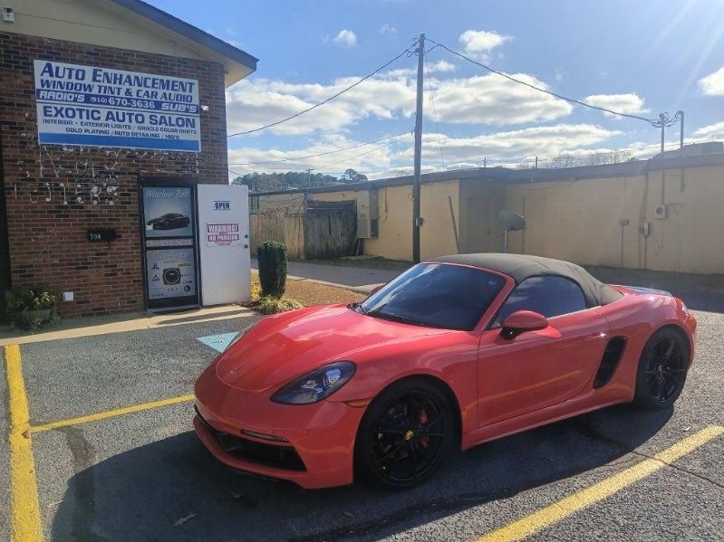A red sports car is parked in a parking lot in front of a building.