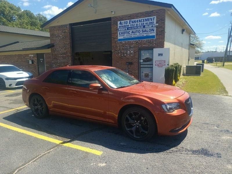 An orange car is parked in front of a brick building.