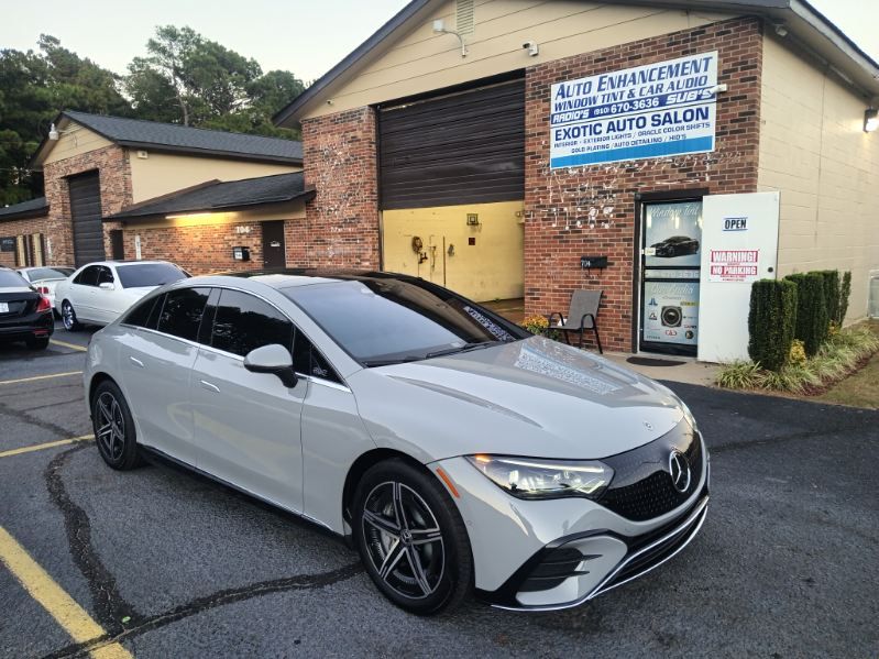 A white car is parked in front of a brick building.