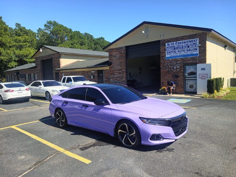 A purple car is parked in a parking lot in front of a building.