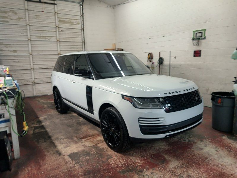 A white range rover is parked in a garage.