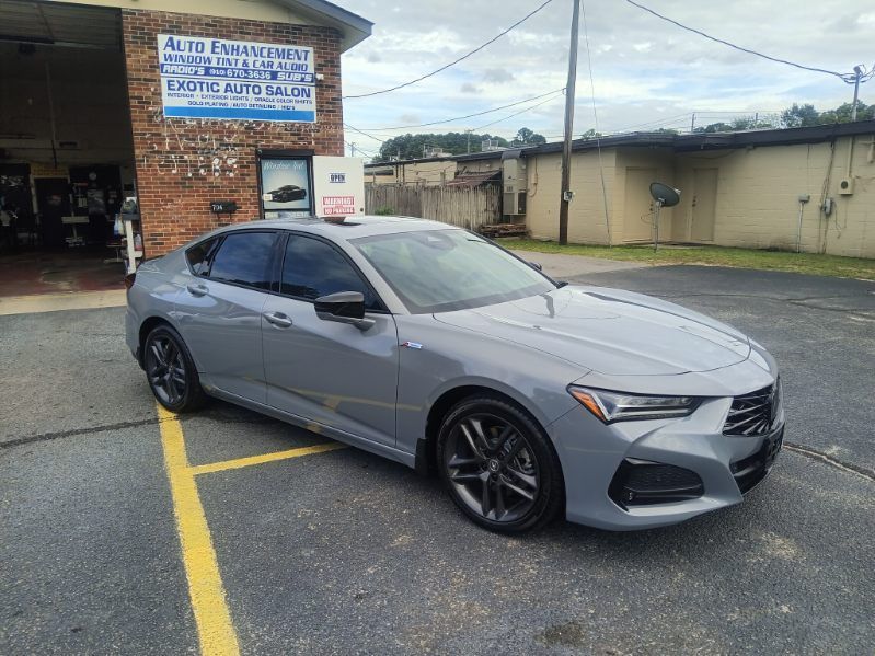 A gray car is parked in a parking lot in front of a building.