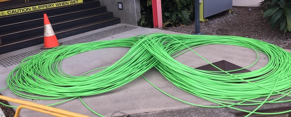 A Bunch of Green Wires Are Laying on the Ground Next to a Cone — Adzcom Civils in Portsmith, QLD