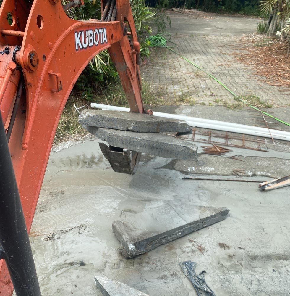 An Orange Excavator Carrying Concrete Slab — Adzcom Civils in Portsmith, QLD